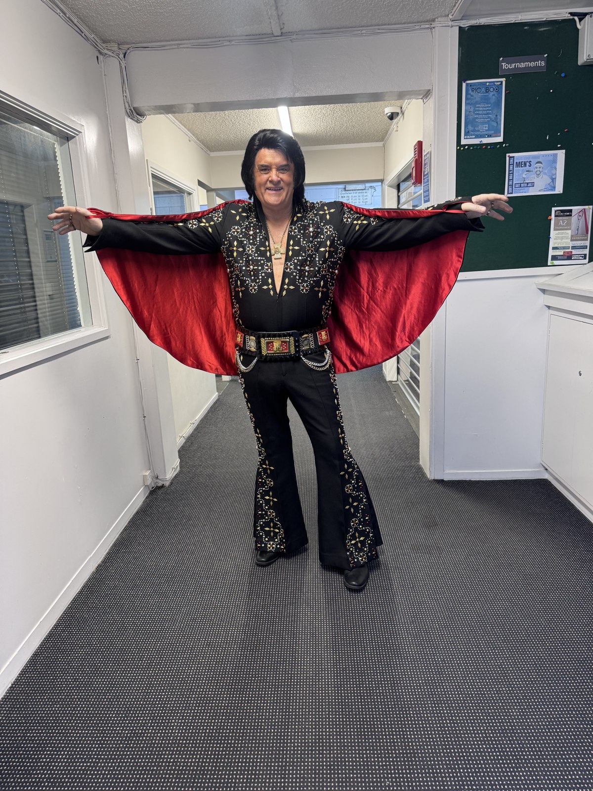 Trevor Needham as Elvis holding out his red-lined rhinestone cape