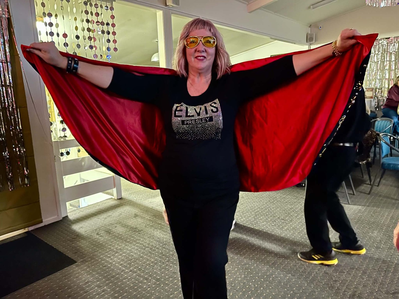 An Elvis fan proudly showing off her Elvis Presley cape at a live show