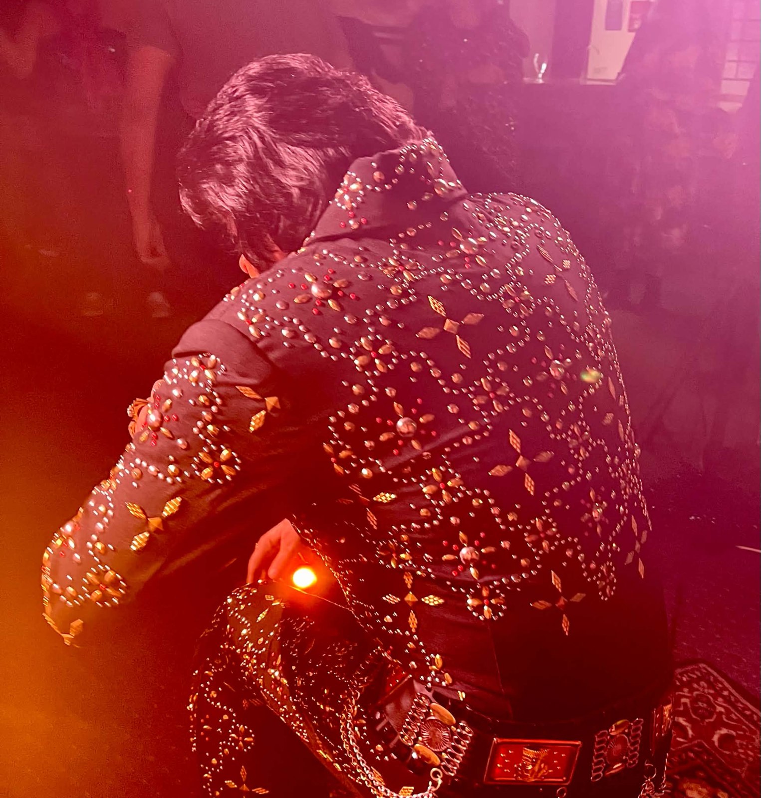 Trevor Needham performing as Elvis in a rhinestone jumpsuit under dramatic stage lighting