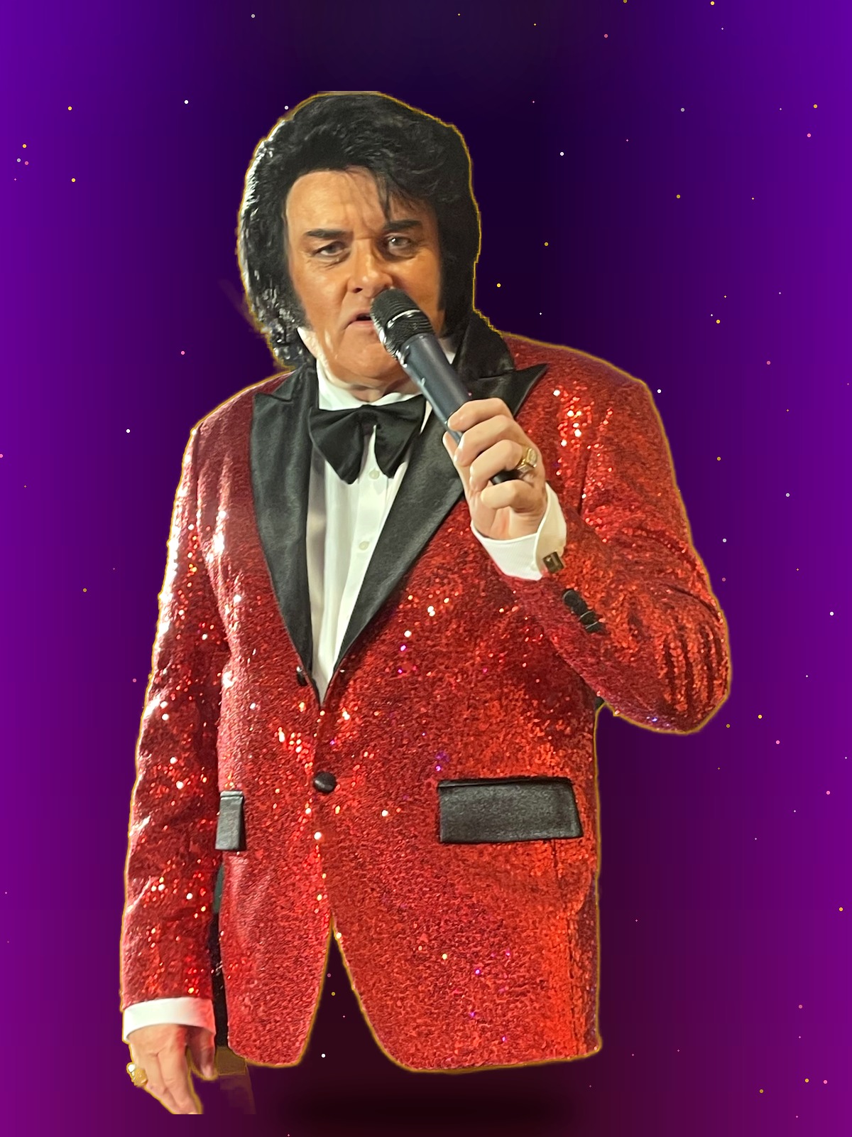 Trevor Needham performing his Engelbert Humperdinck tribute in a sparkling red sequin jacket on a colorful concert stage