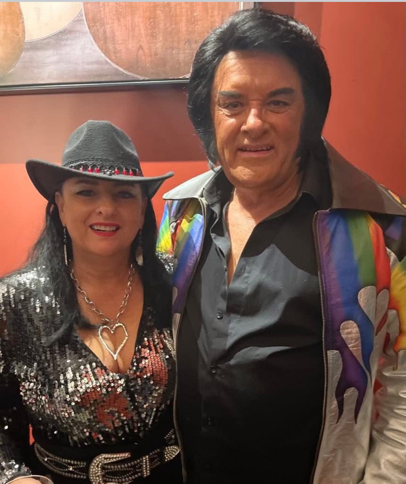 Jannine Douglas performing Queens of Country in a stunning red fringe outfit and cowboy hat at the Grand Ole Opry backdrop