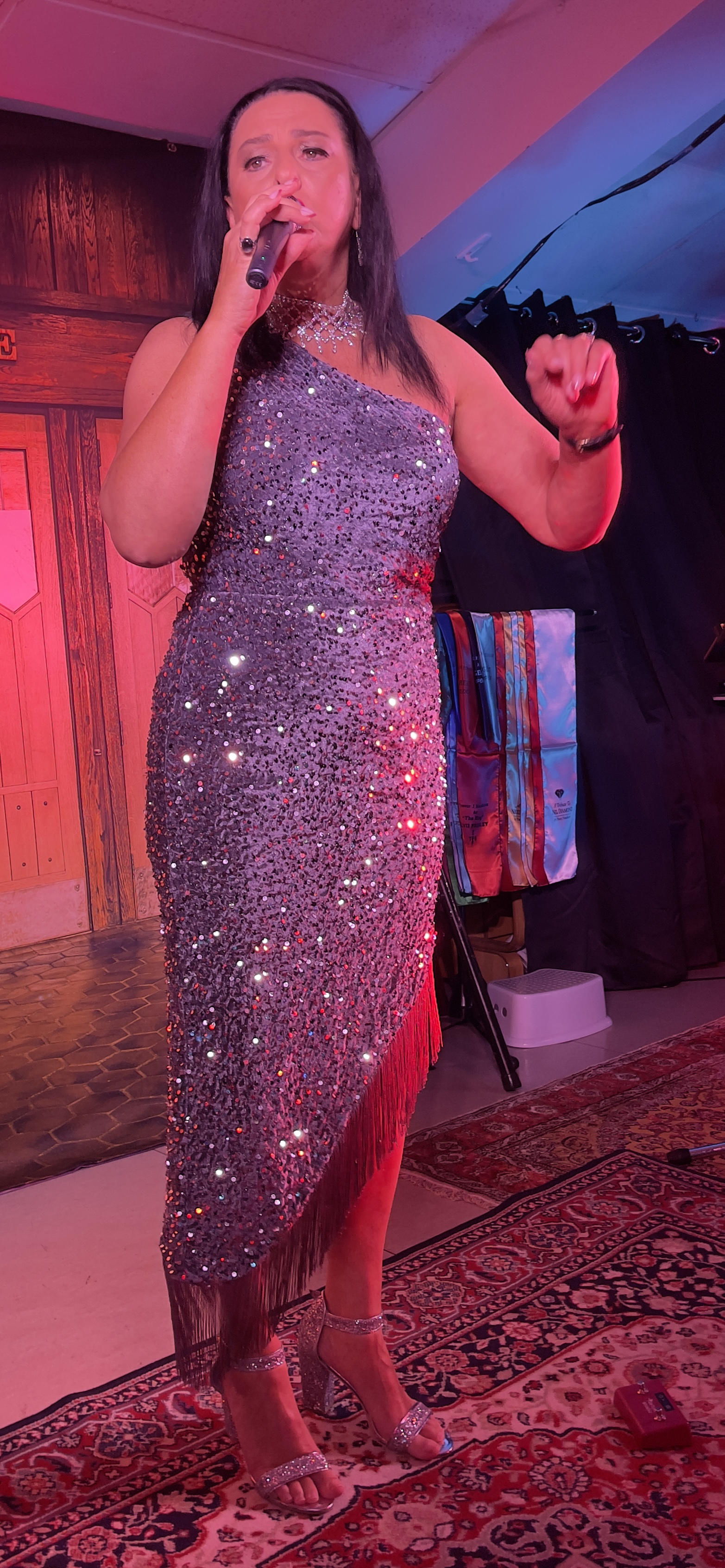 Jannine Douglas performing live in a sparkling sequin dress under colourful stage lights